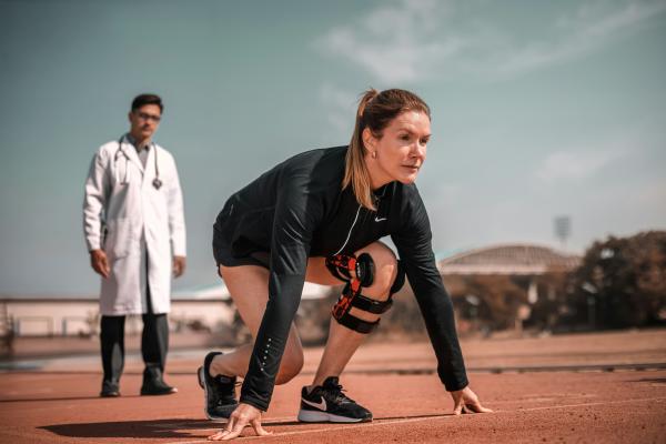 Personne s'aprêtant à faire un sprint, un médecin derrière elle