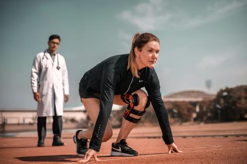 Personne s'aprêtant à faire un sprint, un médecin derrière elle